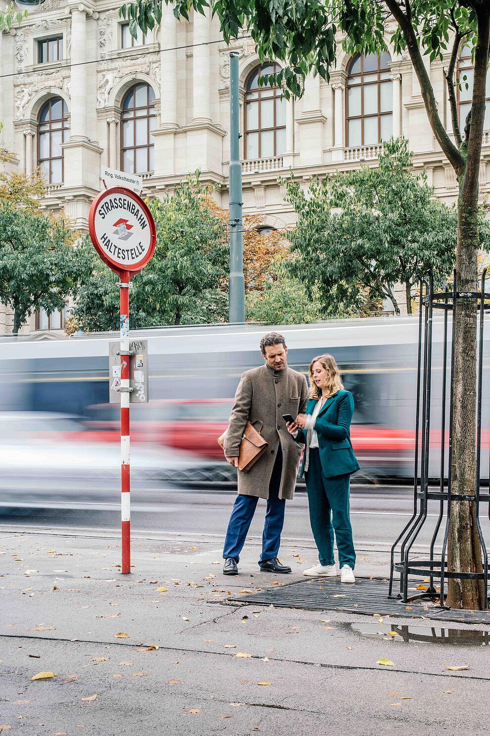 Man and woman standing at the street while tram is passing by 