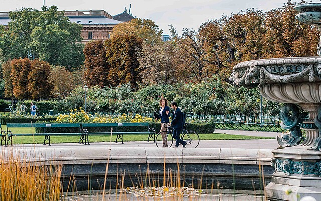 Man and woman walking by a fountain in park